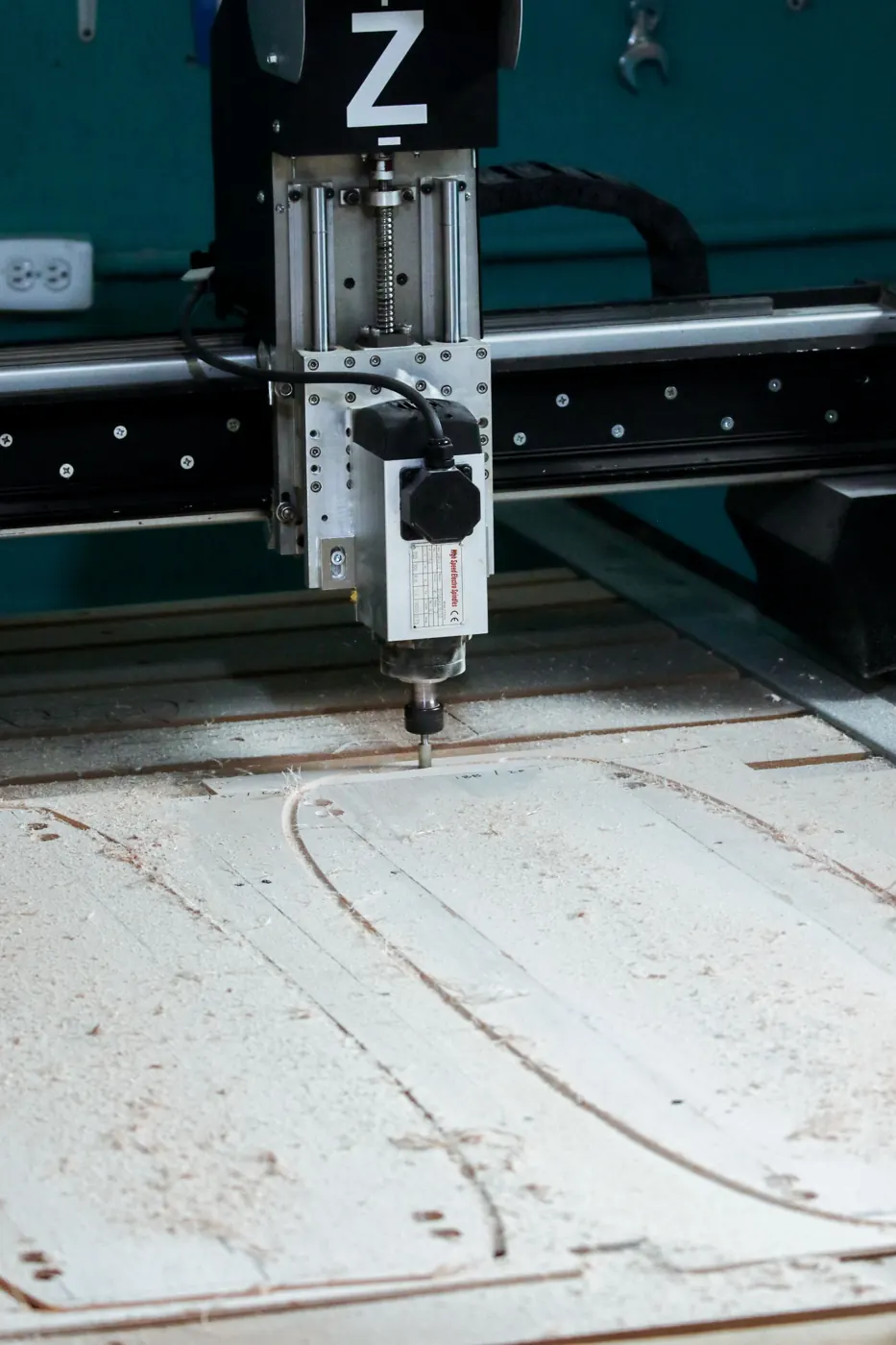 CNC router cutting a curved outline in a wooden board